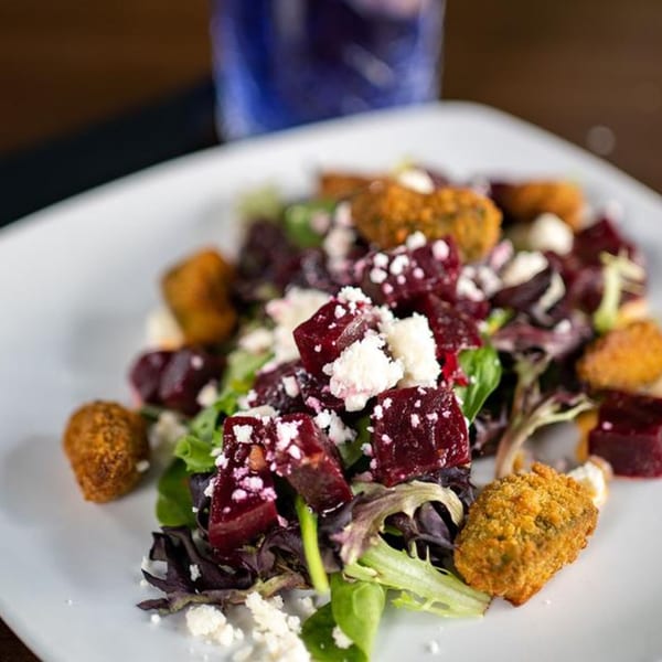 Beet salad with crumbled feta cheese, mixed greens, and crispy fried goat cheese balls.